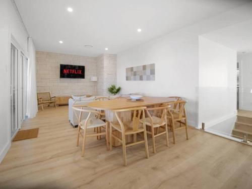 a dining room with a wooden table and chairs at Luxury Home in the Vale in Berkeley Vale