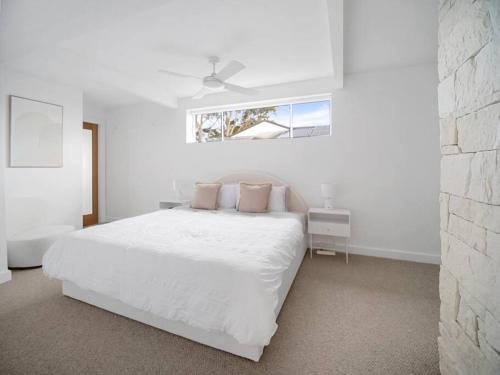 a white bedroom with a white bed and a window at Luxury Home in the Vale in Berkeley Vale
