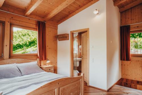 a bedroom with a bed and two windows at Agriturismo Maso Besleri in Cembra