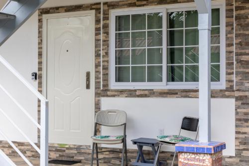 a porch with two chairs and a table and a window at Villas Cozy Sloth in Puerto Viejo