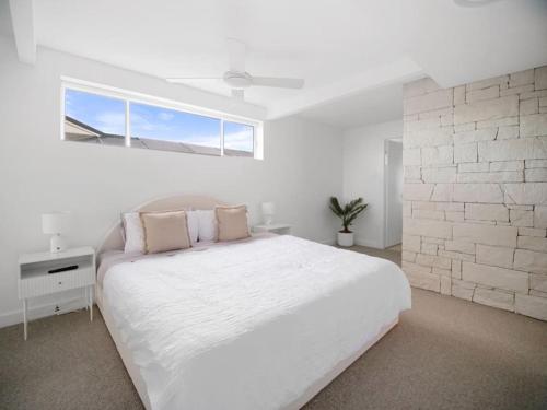 a white bedroom with a large bed and a window at Luxury Home in the Vale in Berkeley Vale