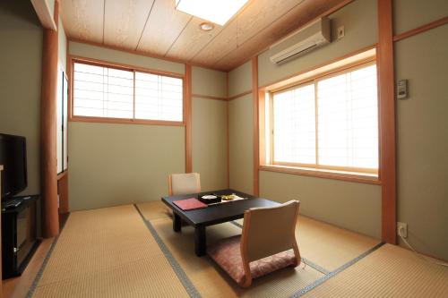 a room with a table and chairs and two windows at 和みの宿 弓ヶ浜いち番館 in Minamiizu