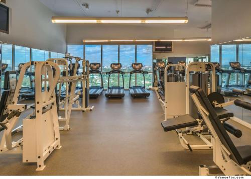 a gym with rows of tread machines and windows at Hotel Arya BW Premier Collection in Miami