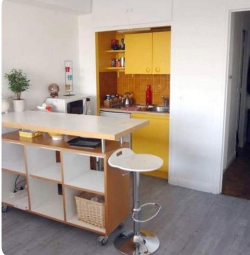 une cuisine avec des armoires jaunes et un comptoir avec un tabouret dans l'établissement Amazing Eiffel views cool area, à Paris