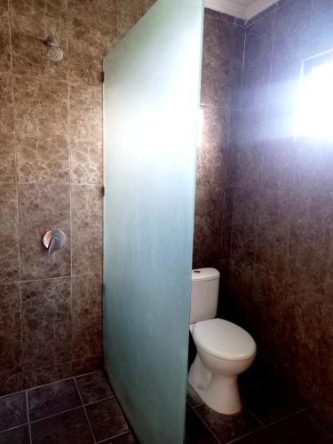 a bathroom with a toilet and a light on the wall at Hotel Omah Cepit in Cepit