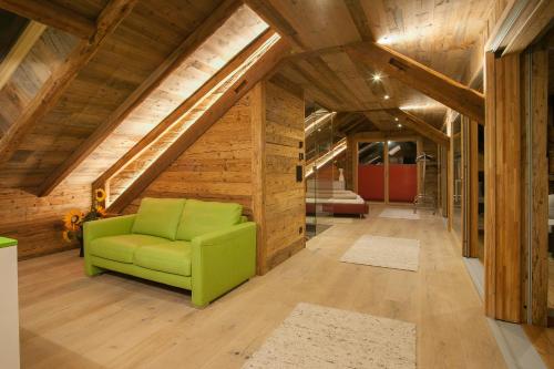 a green chair in a room with wooden ceilings at Neuprantl Apartments in Lana