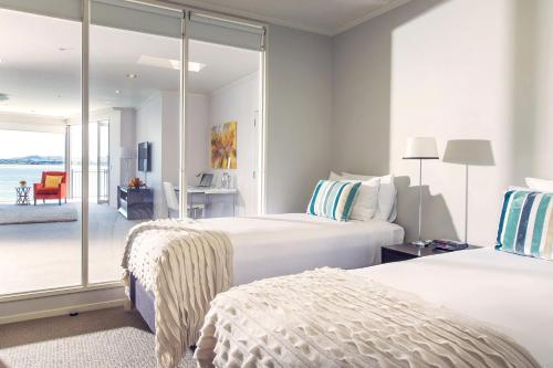 two beds in a hotel room with a balcony at Trinity Wharf Tauranga in Tauranga