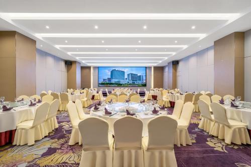 a conference room with tables and chairs and a projection screen at Pearl River International Hotel - Canmetro line 11 YiJing Lu station in Guangzhou
