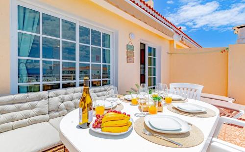 Biały stół z jedzeniem i butelką wina w obiekcie Sunny Arena Sol Apt By Dream Homes Tenerife w mieście Puerto de Santiago