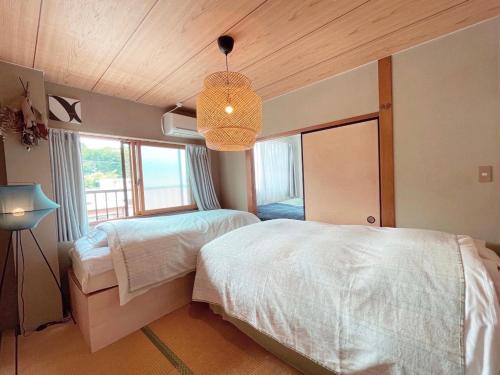 Un dormitorio con dos camas y una lámpara de araña. en 民泊宿 i s e s h i m a 伊勢内宮前203, en Ise