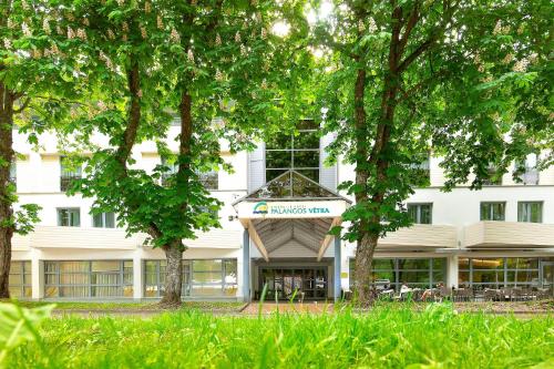 a white building with trees in front of it at Palangos Vetra in Palanga