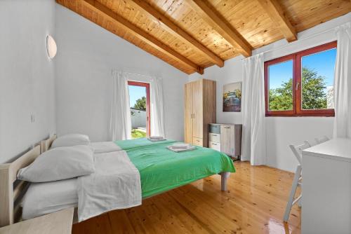 ein Schlafzimmer mit einem Bett mit einer grünen Decke in der Unterkunft Villa Mina - Orihi in Orihi