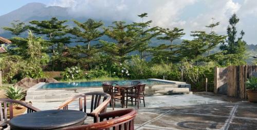 a patio with a table and chairs next to a pool at De Summit Villa & View in Puncak
