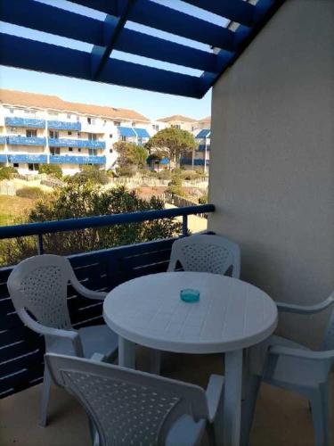 une table blanche et des chaises sur un balcon dans l'établissement Beach Side, à Lacanau-Océan