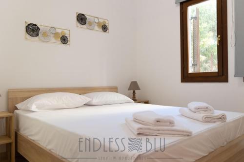 a bedroom with a white bed with towels on it at Endless Blu Apartments in Pyrgadikia