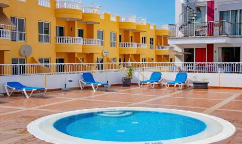 a pool on the side of a building with chairs at Seaside Escape 2bed By Dream Homes Tenerife in Puerto de Santiago
