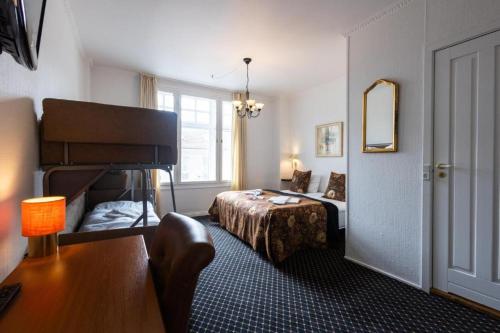 a bedroom with a bed and a table and a mirror at Milling Hotel Saxildhus in Kolding