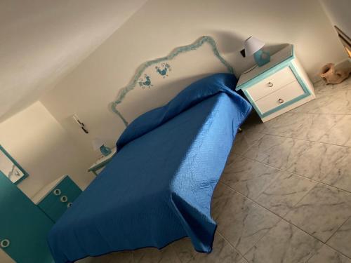 a blue bed with a blue comforter in a bedroom at Cià Evelina in SantʼAntìoco