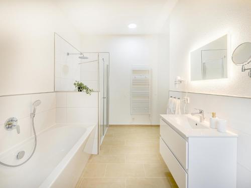 a white bathroom with a tub and a sink at FLAIR Homes - Design Apartments with Smart-TV, Self Check-in & Free Parking in Karlsruhe