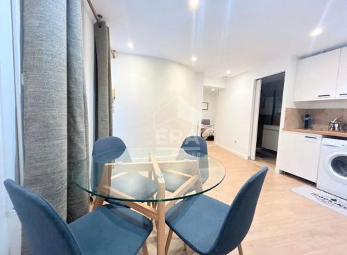 une table en verre avec des chaises bleues dans la cuisine dans l'établissement 2 pièces meublé neuf Pertuis, à Pertuis