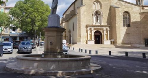 une fontaine au milieu d'une rue devant une église dans l'établissement 2 pièces meublé neuf Pertuis, à Pertuis