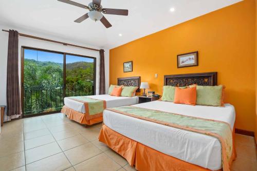two beds in a room with a large window at Leyenda Boutique Hotel & Spa in Sámara