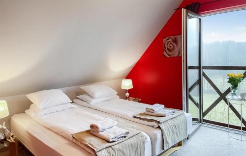 a bedroom with two beds and a red wall at Pet Friendly Home In Szarejki With Wifi in Szarejki