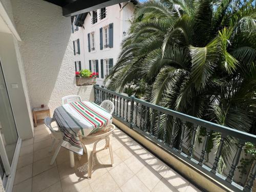 d'un balcon avec une table, des chaises et un palmier. dans l'établissement Appartement avec grand balcon, piscine et parking, à Biarritz
