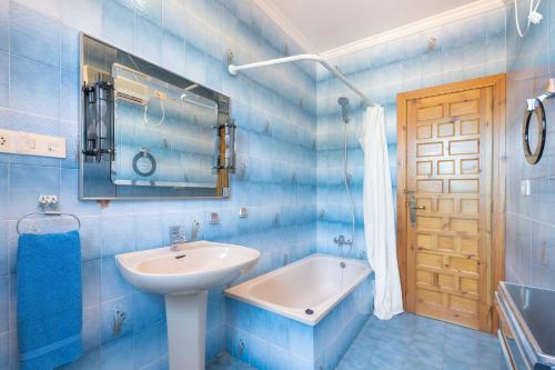 a blue tiled bathroom with a sink and a mirror at El Cachorro in Altura