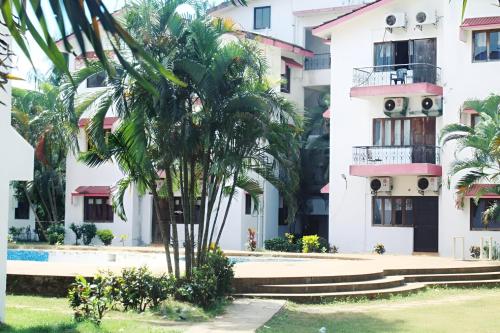 a palm tree in front of a building at Ronne's Little Baga service apartments in Goa