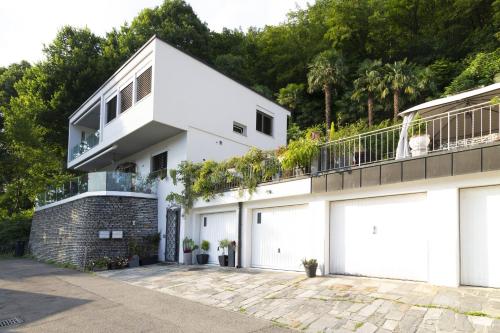 a white house with a balcony and white garage doors at Apartment Design - Terrazzo, vista lago mozzafiato in Caslano