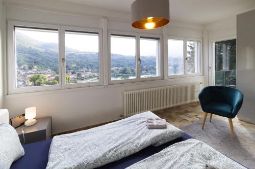 a bedroom with a bed and a chair and windows at Apartment Design - Terrazzo, vista lago mozzafiato in Caslano