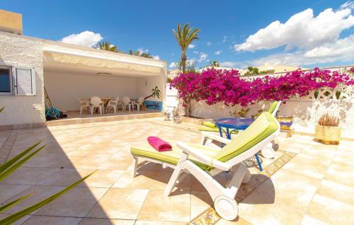 un patio avec deux chaises longues et des fleurs roses dans l'établissement Cozy Home In Torrevieja With Wifi, à Torrevieja