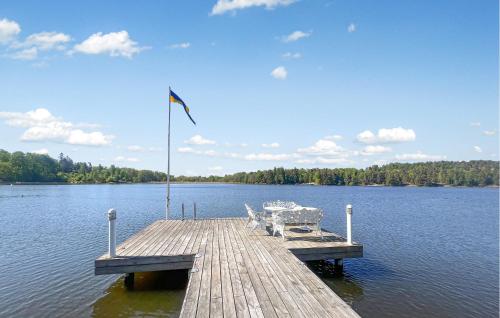 a dock with two chairs and a flag on a lake at Stunning Home In Södertälje in Södertälje
