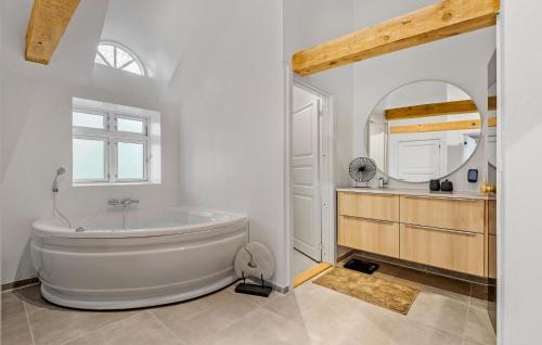 a bathroom with a large tub and a mirror at Nice Home In Janderup Vestj With Sauna in Billum