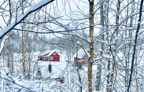 a red house in a snow covered forest with trees at 2 Bedroom Gorgeous Home In Hallaryd in Hallaryd