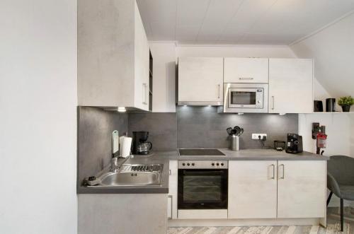 a kitchen with white cabinets and a sink and a microwave at Ferienwohnung City in Emden