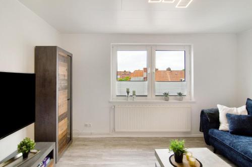 a living room with a blue couch and a window at Ferienwohnung City in Emden
