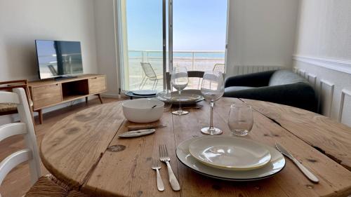 une table en bois avec des assiettes et des verres à vin dessus dans l'établissement La Vigie: Sérénité en Bord de Mer, à Cayeux-sur-Mer