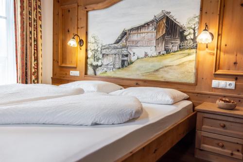 two beds in a room with a painting on the wall at Hotel Pension Odles in San Martino in Badia