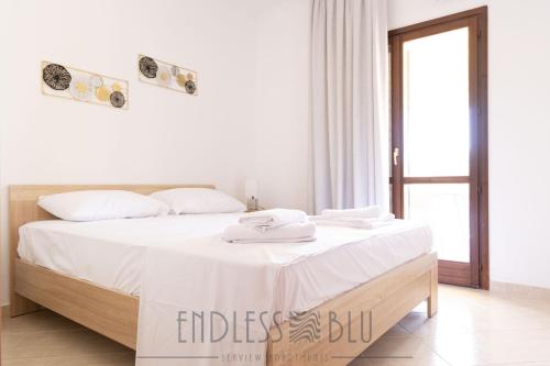 a white bedroom with a large bed with white sheets at Endless Blu Apartments in Pyrgadikia