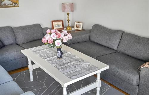 a living room with a couch and a table with flowers at 3 Bedroom Gorgeous Apartment In Borhaug in Borhaug
