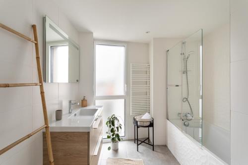 une salle de bain blanche avec un lavabo et une douche dans l'établissement Namasté - Bel appt pour 5 avec terrasse parking, à Rennes