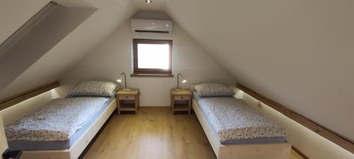 two beds in a attic room with a window at Green Garden Apartment in Bled