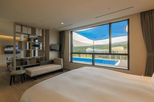a bedroom with a bed and a large window at Hotel Nanta Jeju in Jeju