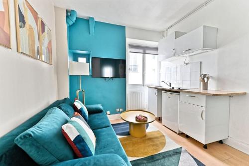 un salon avec un canapé bleu et une cuisine dans l'établissement Appartement cosy et coloré au cœur de Paris, à Paris