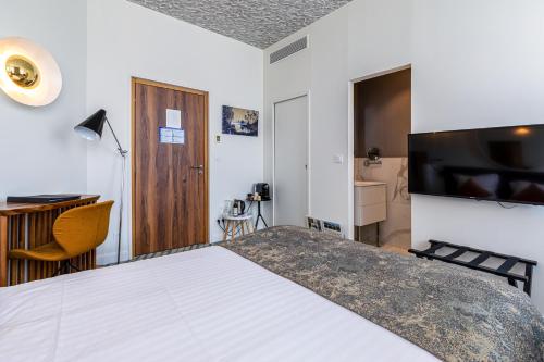 a bedroom with a bed and a desk and a television at Hotel Le Saint Gelais in Angoulême