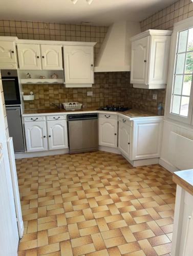 une cuisine avec des armoires blanches et un plancher en bois dans l'établissement Enosis, à Port-en-Bessin-Huppain