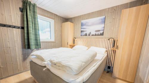 a bedroom with a large bed with white sheets at Lakeview II Vrådal Hyttegrend in Vradal