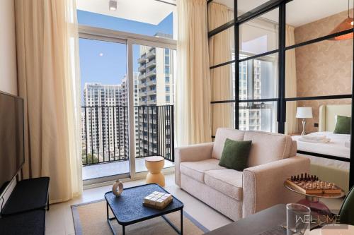 a living room with a couch and a large window at WelHome - Fancy 1BR Apt at Dubai Hills near Dubai Hills Mall in Dubai